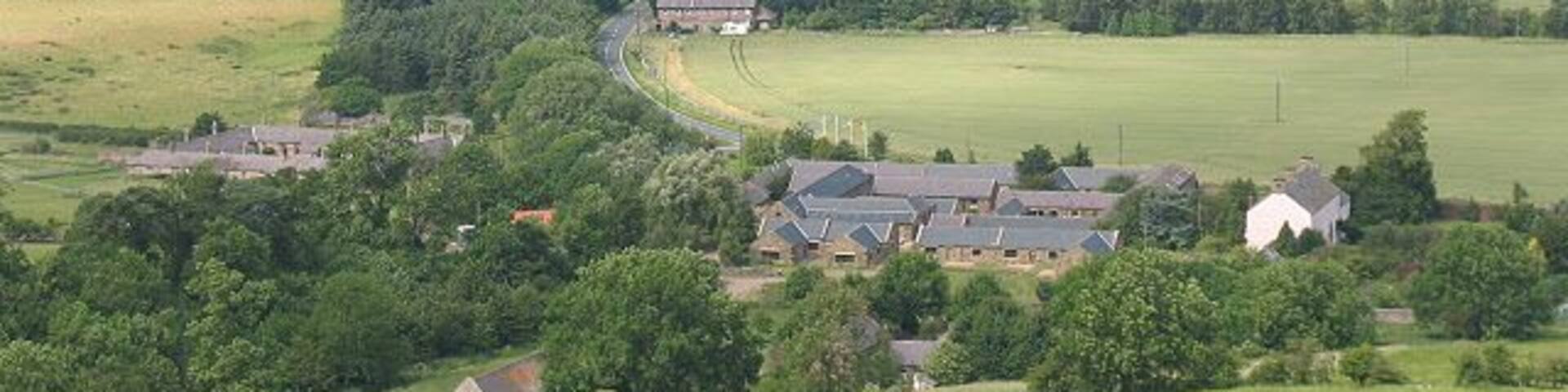 View over Akeld from the south. The large complex of buildings in the foreground of the photo is the country club 1248370, which dominatees the settlement. A little further along the main road is the old station 309714.