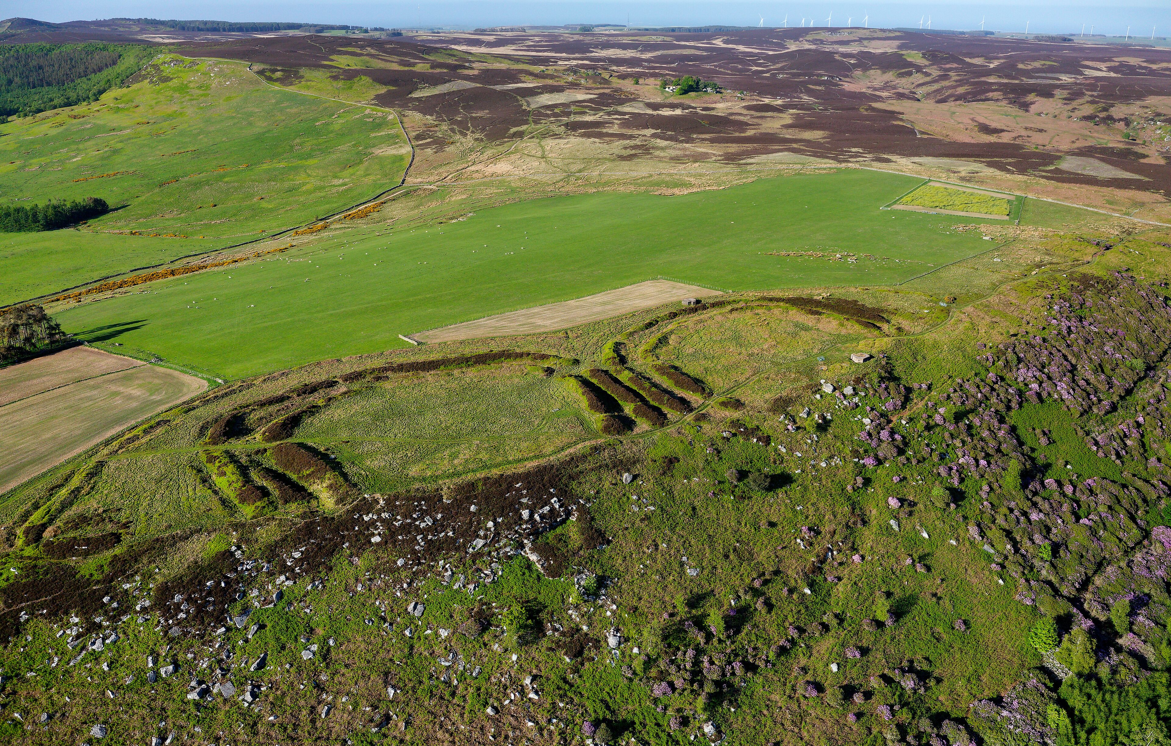 The twin forts of Old Bewick multivallate Iron Age hillfort south east of Wooler, Northumberland. Aerial view over scarp edge to north east