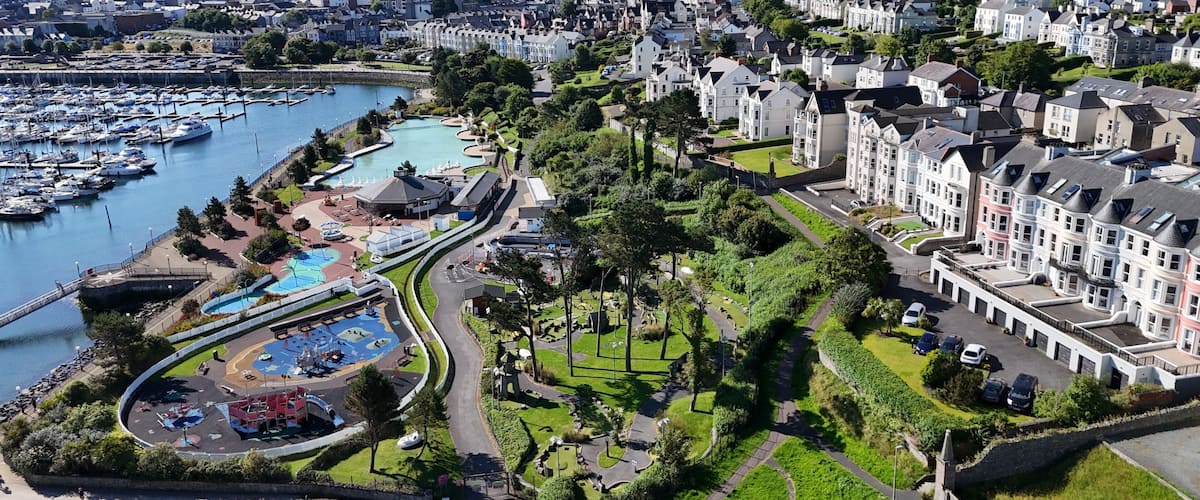 A coastal town with a marina, residential buildings, and a park with a playground.