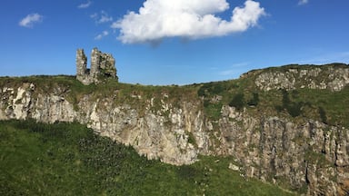 A rocky cliff with ruins and a clear blue sky.