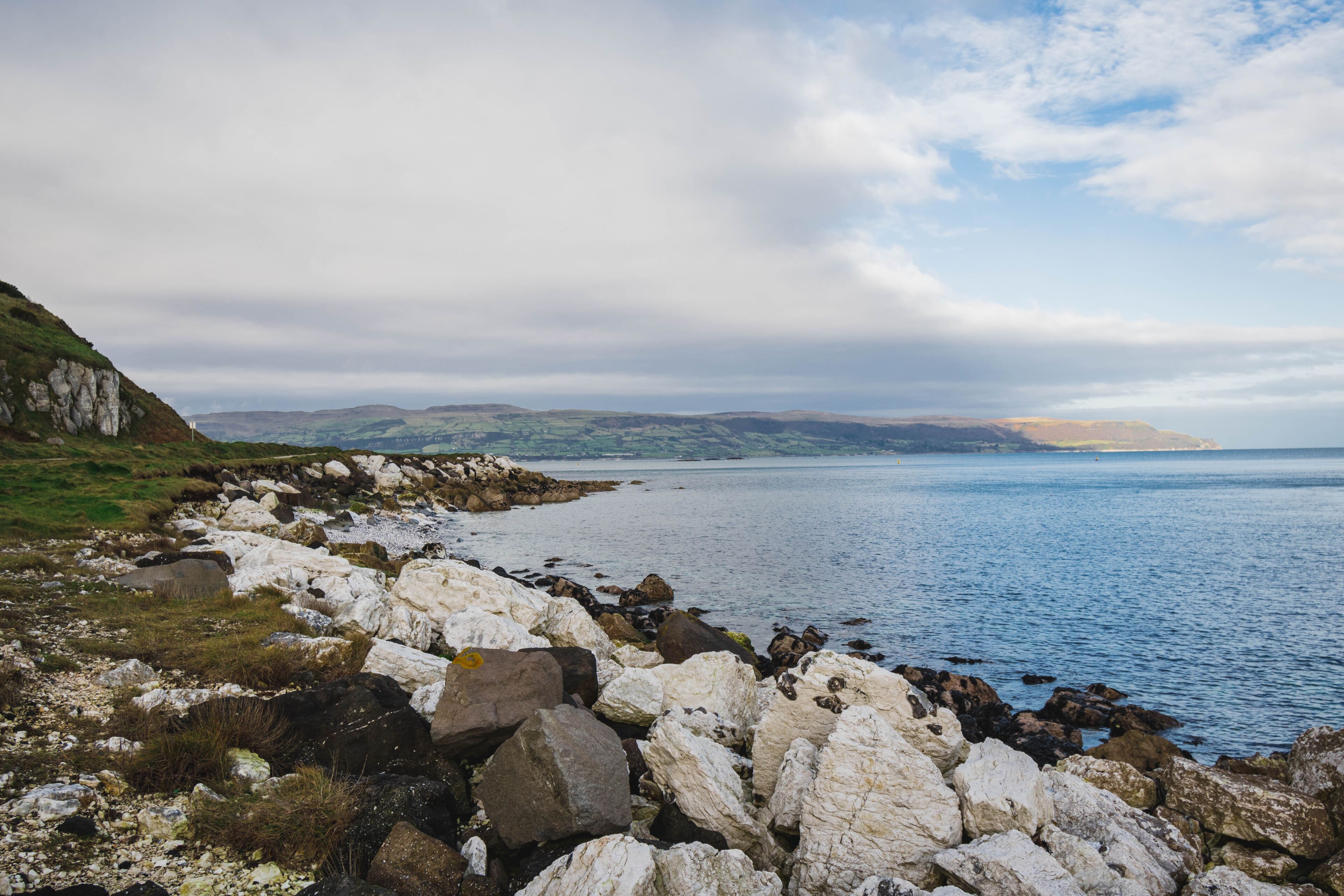 Path Glenarm Coastal Path, south of the village of Glenarm, in Northern Ireland,  large white boulders and distant mountains