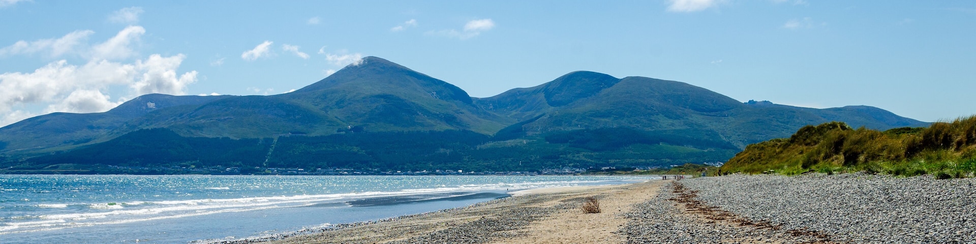 A pebbly beach with mountains in the background.