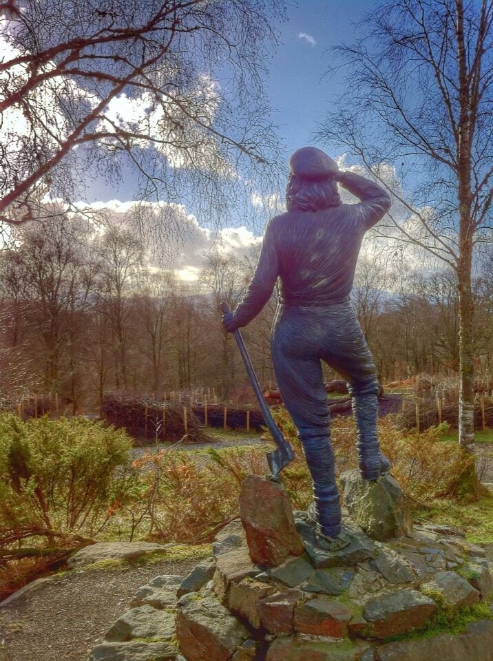A statue of a Lumberjill. 

Formed in 1942 to help with increased demand for timber during the Second World War. Lumber Jills replaced Lumber Jacks. Around 6000 woman worked in the forest and this a memorial to their efforts. 