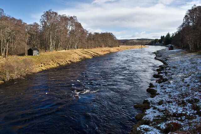 River Dee below Dinnet Bridge It is mid morning and overnight snow has already melted on the north bank but remains in the shade of the trees on the south bank. The huts are for use by those who are fishing on the river. There was no one on the banks as, in Scotland, fishing is not allowed on Sundays for salmon and other migratory fish.