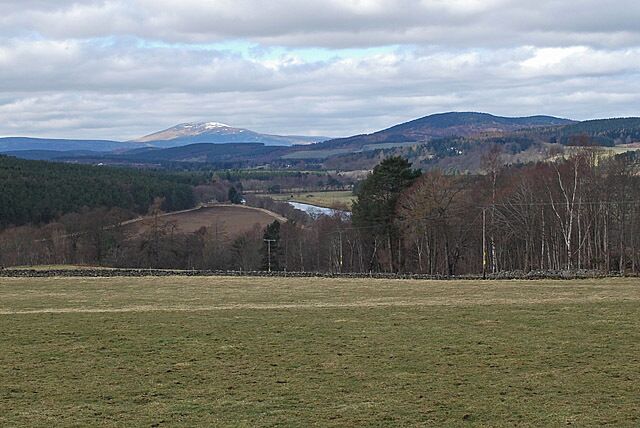 A mountainous landscape with a river, a bridge, and a forested area.