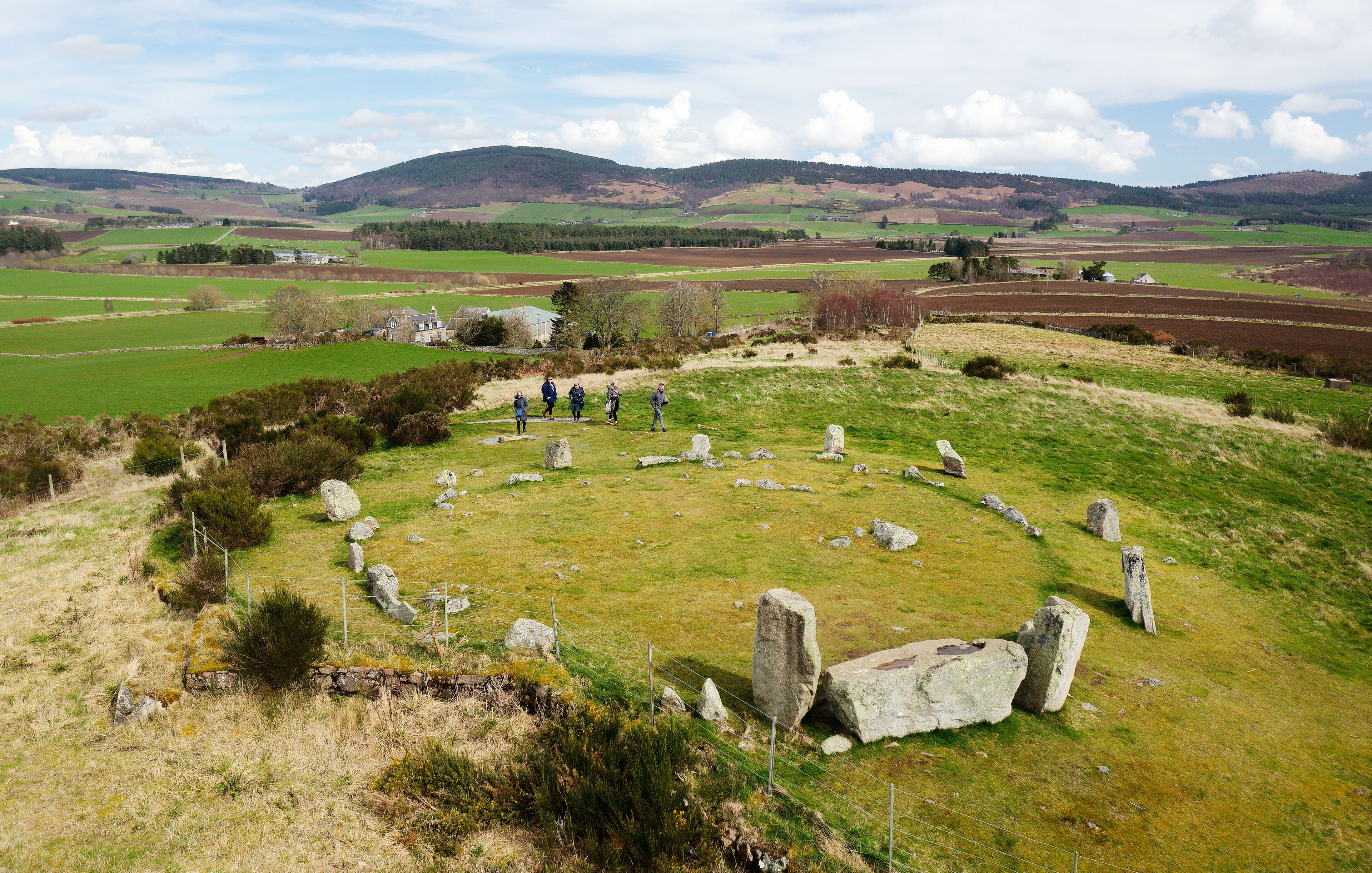 A stone circle in a grassy field with rolling hills in the background.