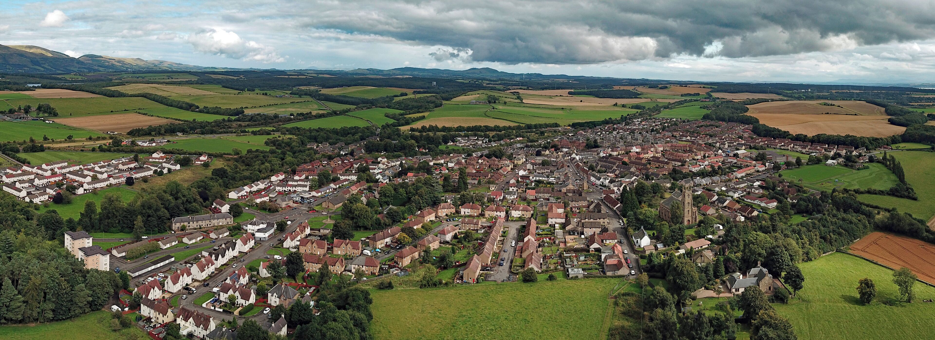 An aerial view of a town surrounded by green fields and mountains.