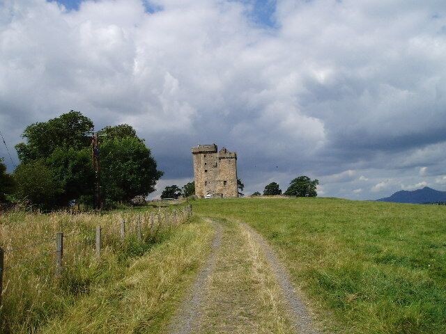 A rural landscape with a stone tower and a dirt path leading to it.