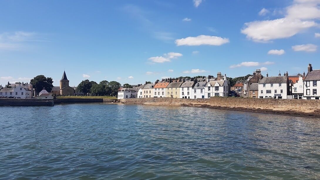 A coastal town with white buildings, a church, and a calm sea.