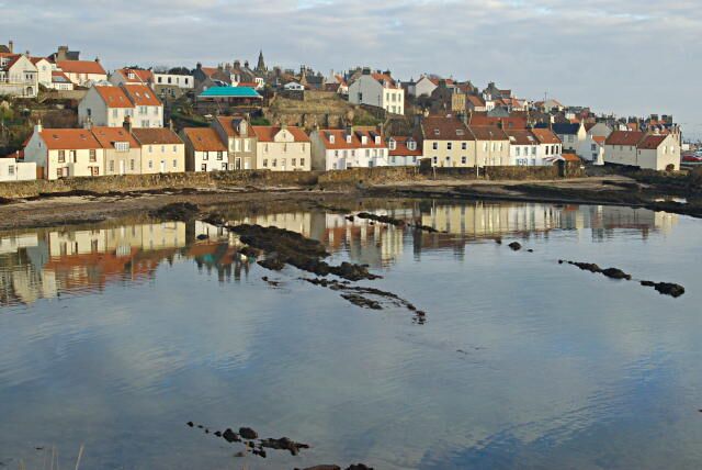 A coastal town with buildings reflected in calm water.
