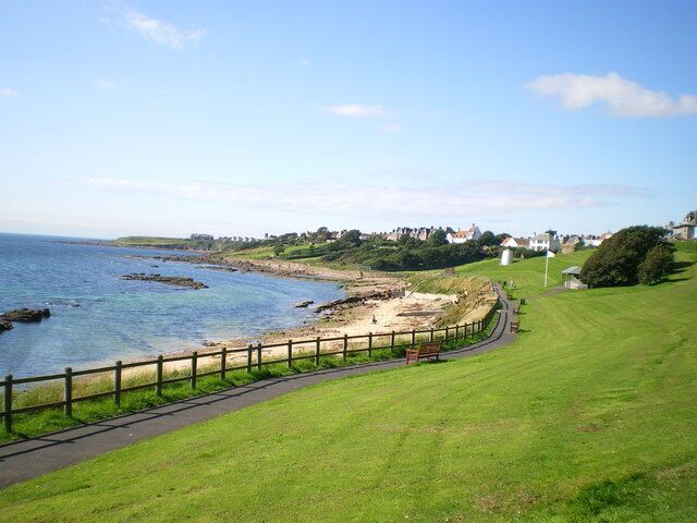 Roome Bay from the eastern end.. The park is basically located on a raised beach, of which there are better examples all along this stretch of the coastline. The white building at the far end of the grass is the Crail doocot 217203 and 482806.