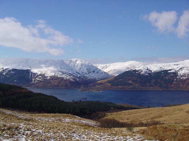A mountainous landscape with a lake and snow-covered peaks.
