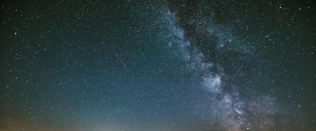 A starry night sky over a hilly landscape with a visible Milky Way.