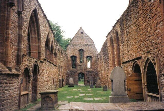 An ancient stone building with arched doorways and a central tower.