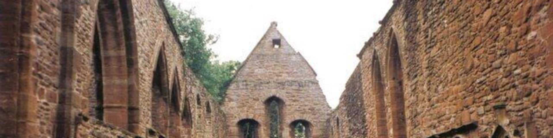 An ancient stone building with arched doorways and a central tower.