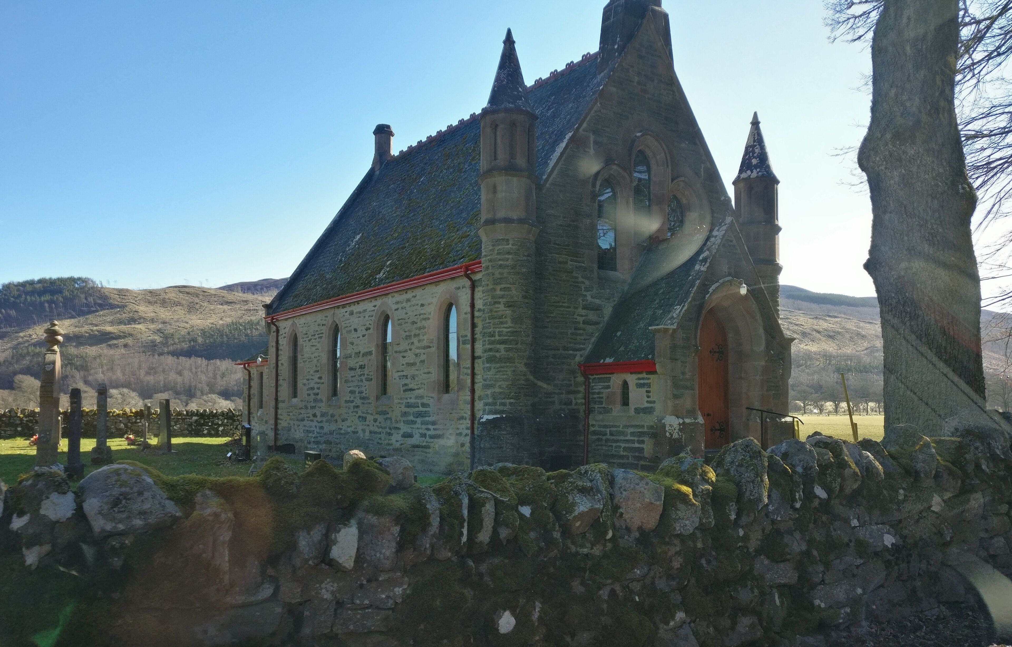 A stone church with a steeply pitched roof and a bell tower.