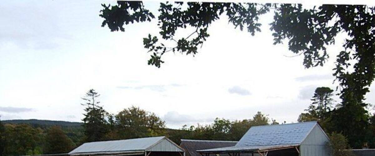 A farm with multiple barns and a large grassy field.