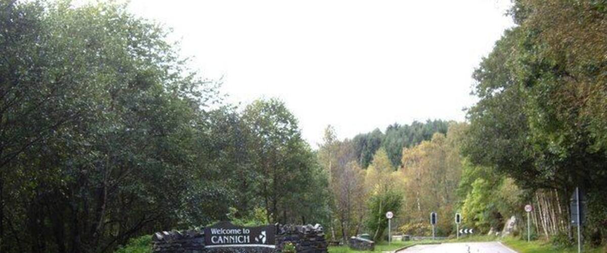 A road leading into a forested area with a welcome sign for CANNICH.