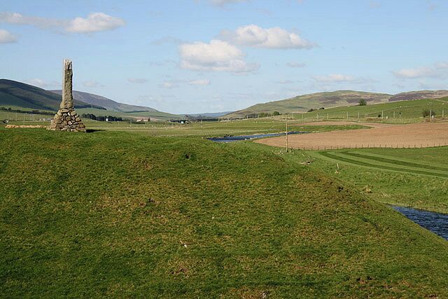 A Motte and Bailey at Abington. These earthworks on the west side of the River Clyde date back to the early 12th century. The monument on the left 1305842 is dedicated to Matthew McKendrick, a former postmaster at Abington and keen angler.