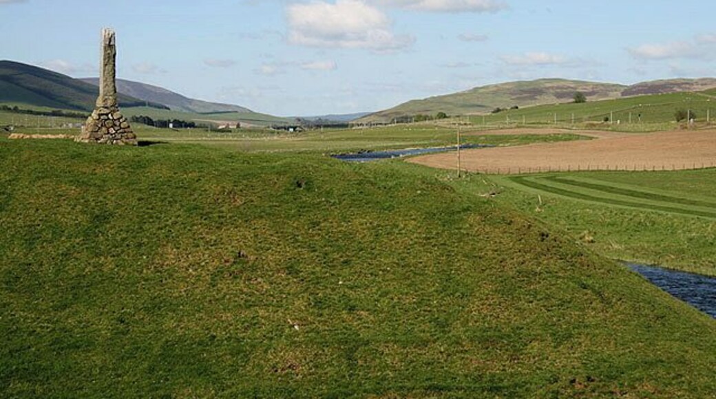 A Motte and Bailey at Abington. These earthworks on the west side of the River Clyde date back to the early 12th century. The monument on the left 1305842 is dedicated to Matthew McKendrick, a former postmaster at Abington and keen angler.