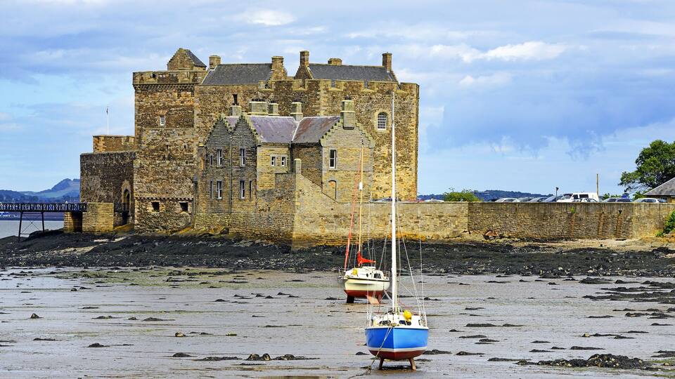 A castle by a beach with two boats.