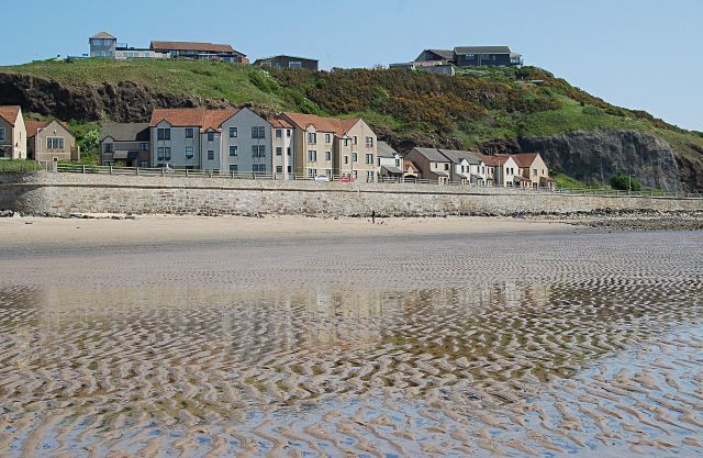 A beach with houses on a hillside.