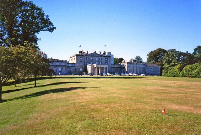 A large, historic building with a lawn in front.