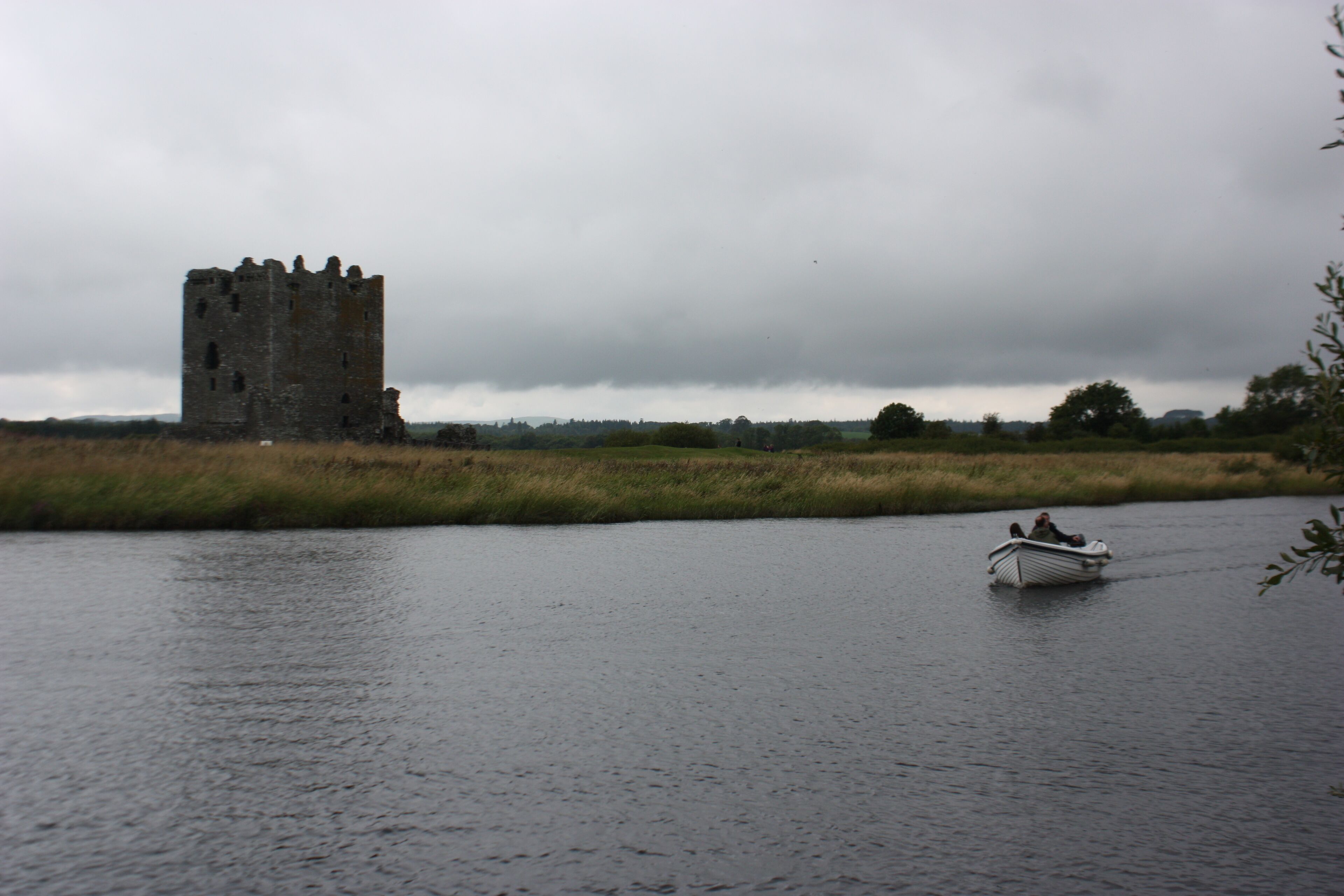 A castle by a river with a boat in the foreground.