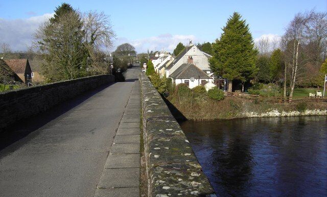 A stone bridge over a river, surrounded by houses and trees.