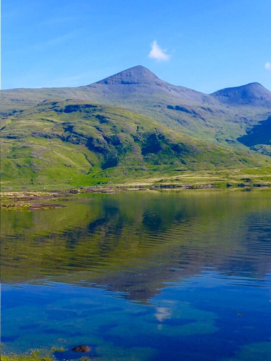 A mountain range with a lake reflecting the sky.