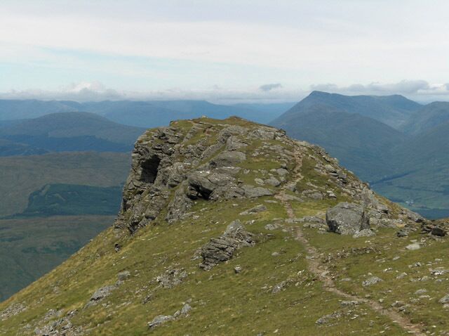 A rocky mountain peak with a grassy path leading up.