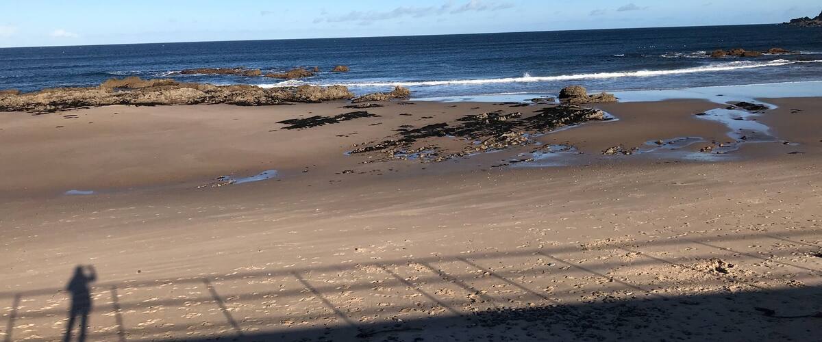 A sandy beach with scattered rocks and waves crashing onto the shore.
