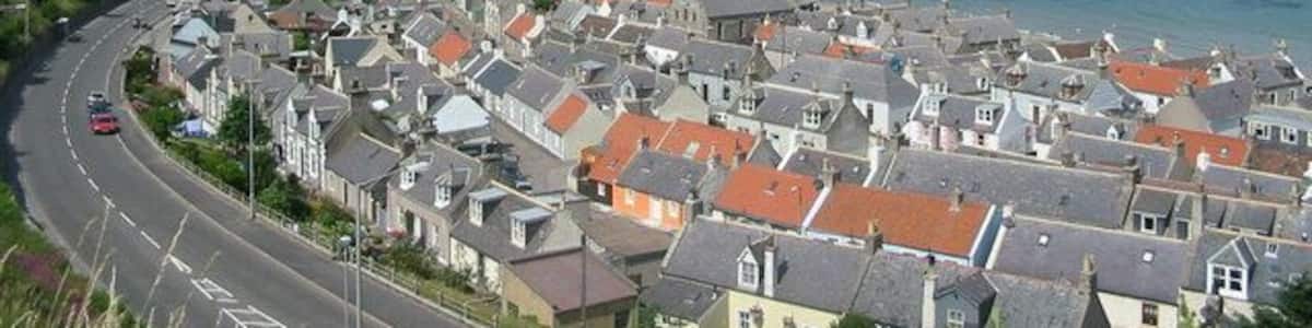 Une ville côtière qui se distingue par un imposant viaduc, une plage et un ciel d’un bleu limpide.