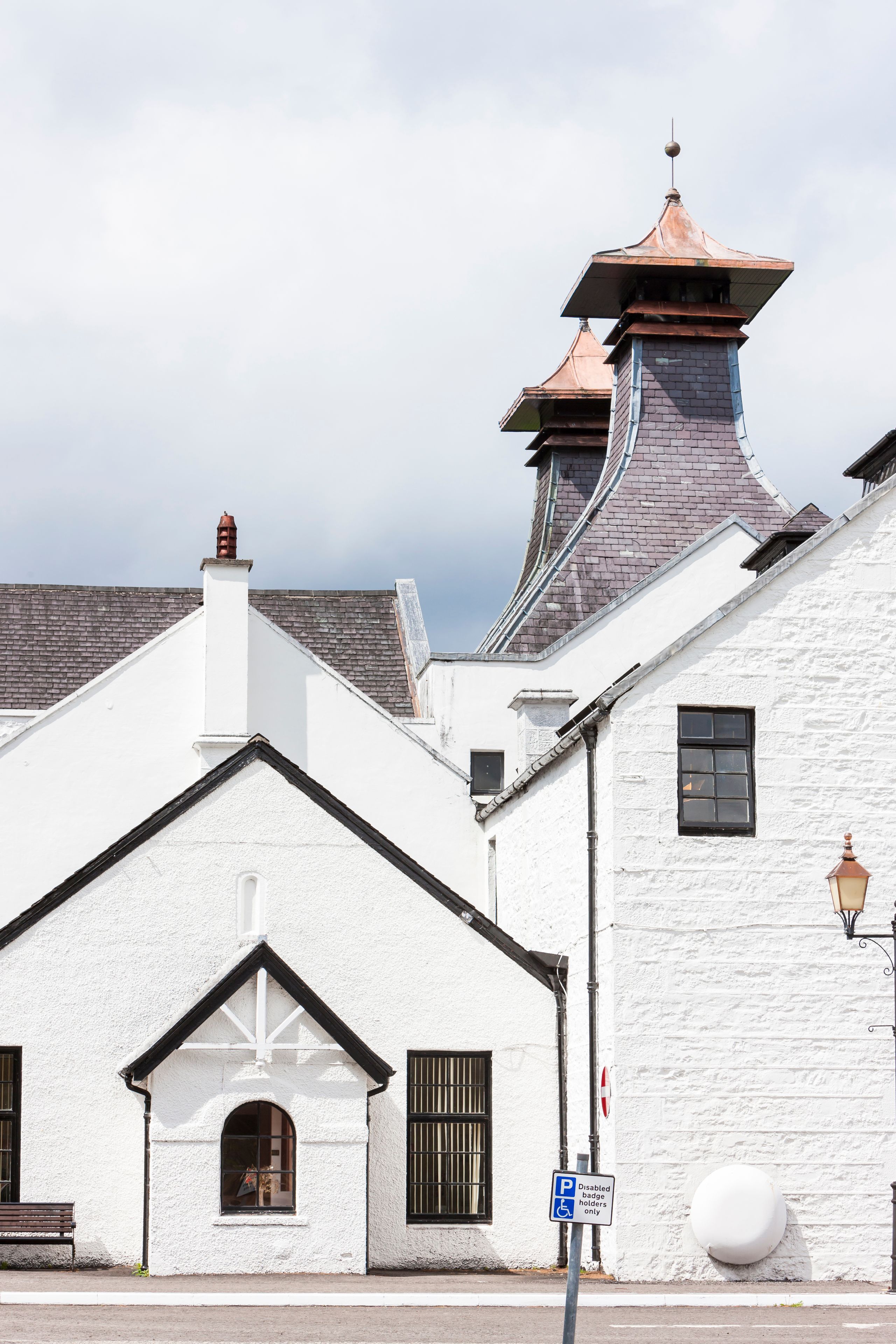 A white building with a black roof, a chimney, and a street lamp.