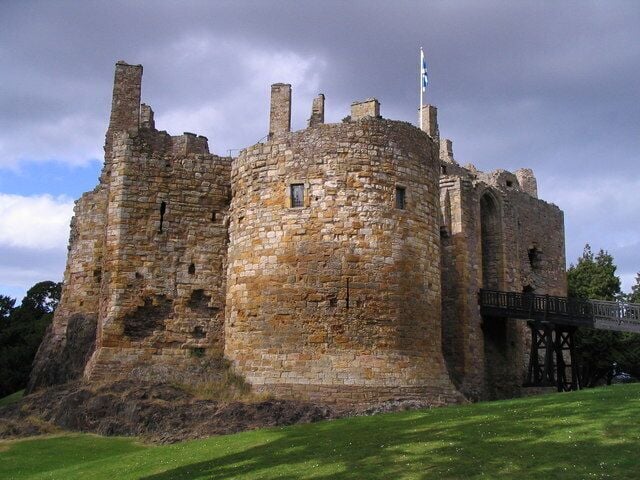 A historic stone castle with a round tower and a flag.