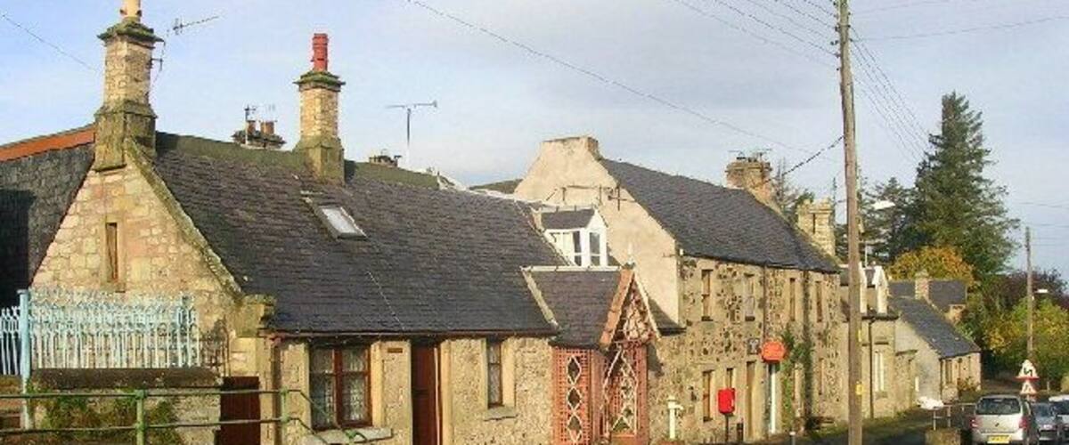 A stone building with a red door and a small garden in front.