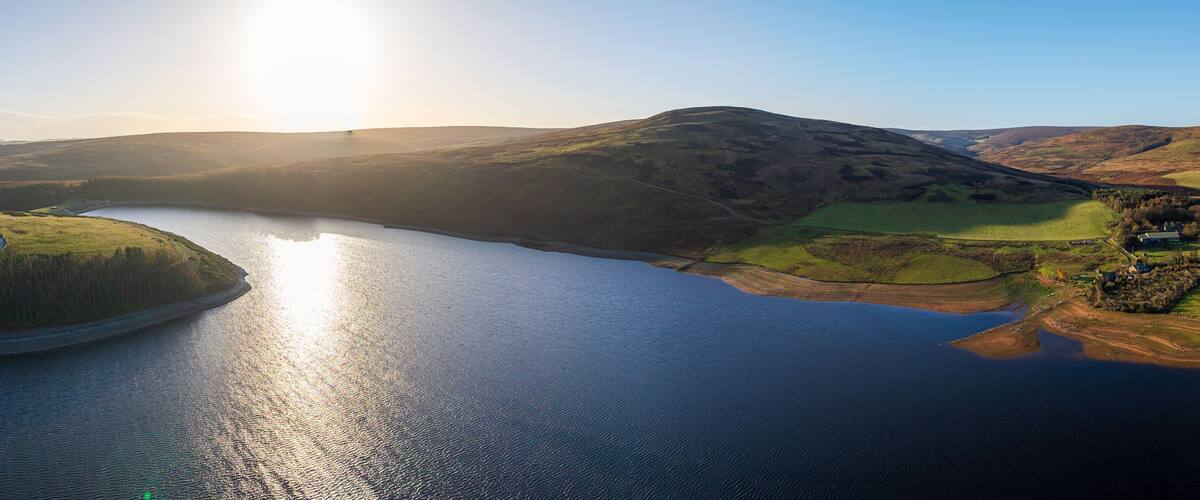 A lake surrounded by rolling hills and a small village.