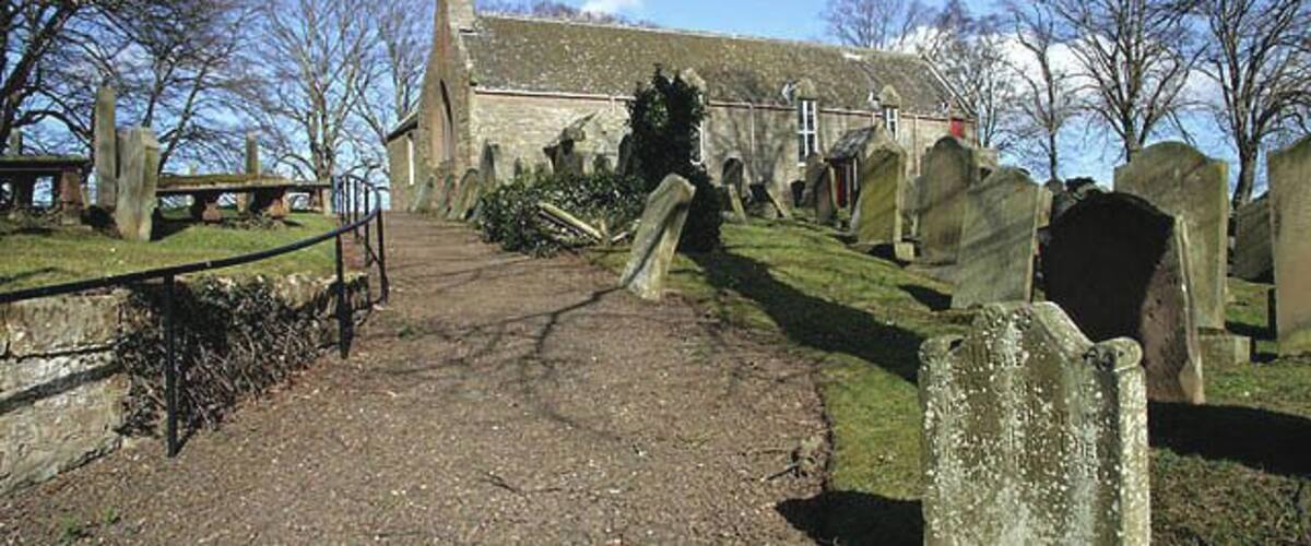 A cemetery with headstones, a church, and a pathway.
