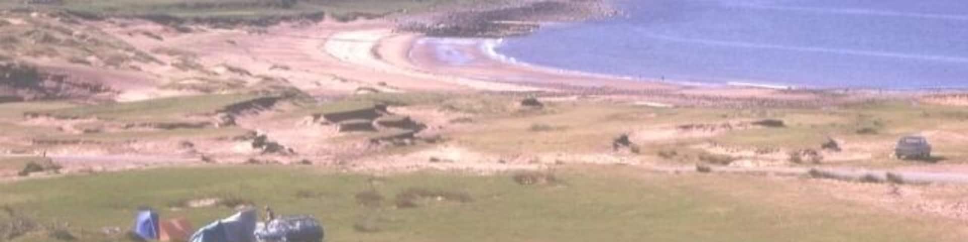 Opinan. The wind has built up and partly destroyed the dunes around this exposed beach.