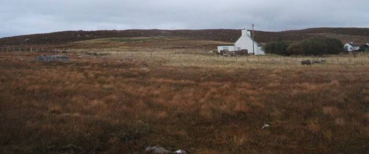 A white church in a grassy field with rolling hills in the background.