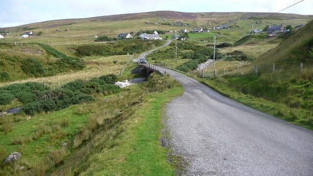 Melvaig village Single-track road crosses a small stream approaching the village of Melvaig.