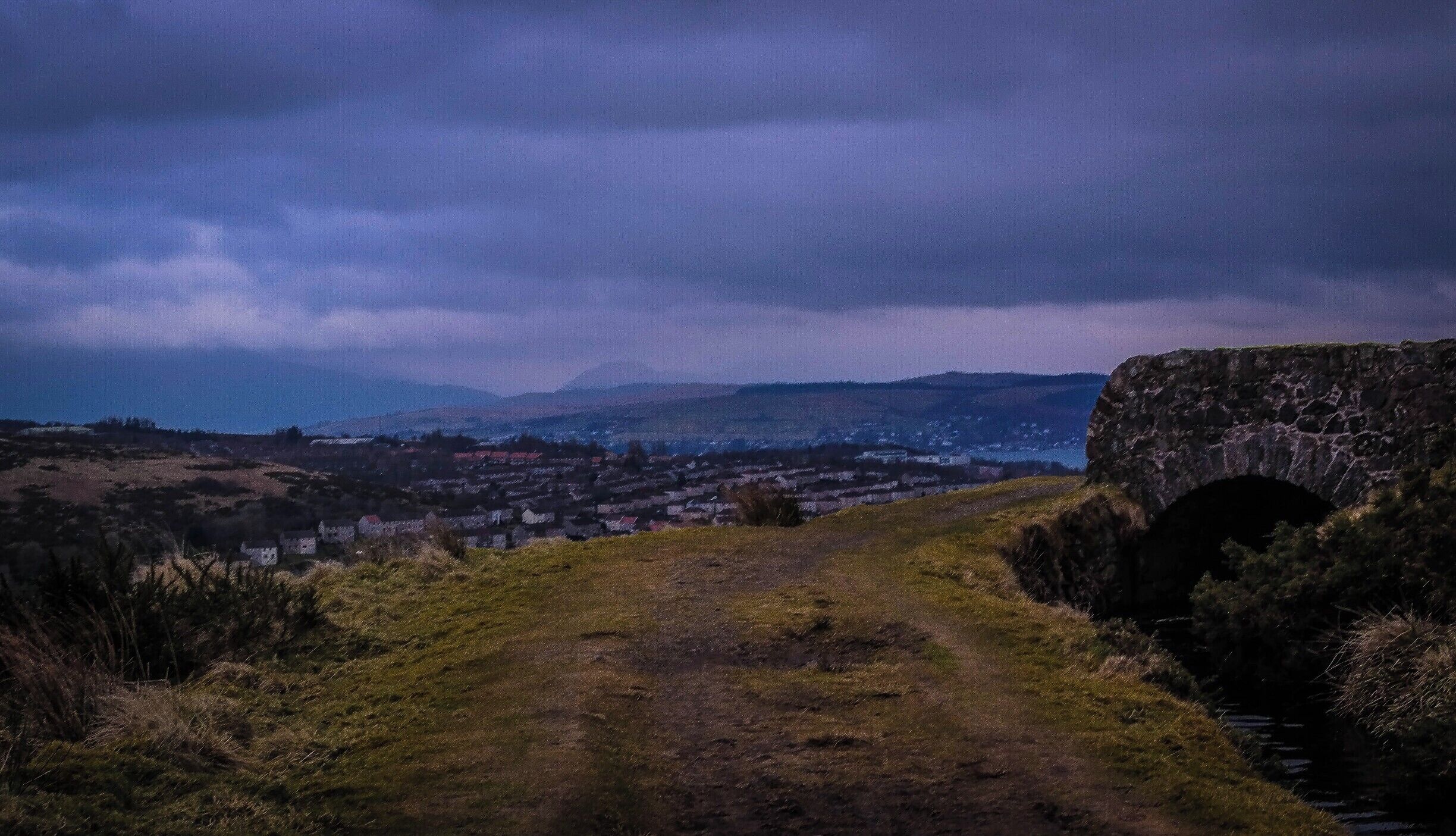 The Greenock Cut walk is a 7 miles circular mostly following the ' Greenock Cut ' a water system that was designed and built by Robert Thom in 1827. It has now been designated an ancient monument in recognition of the significant role it played in the industrial revolution. In this view, looking north, the faint outline of Ben Lomond is visible on the distant horizon.
