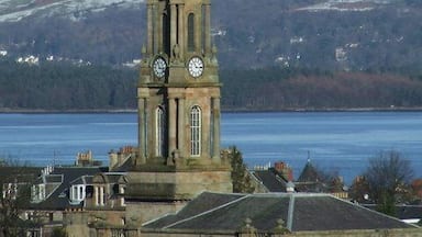 A church tower with a clock, set against a backdrop of a snowy mountain and a body of water.