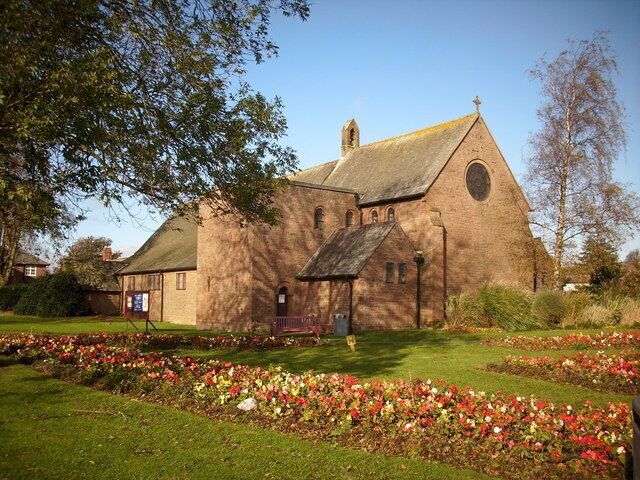 A church with a bell tower, surrounded by a well-maintained garden with colorful flowers.