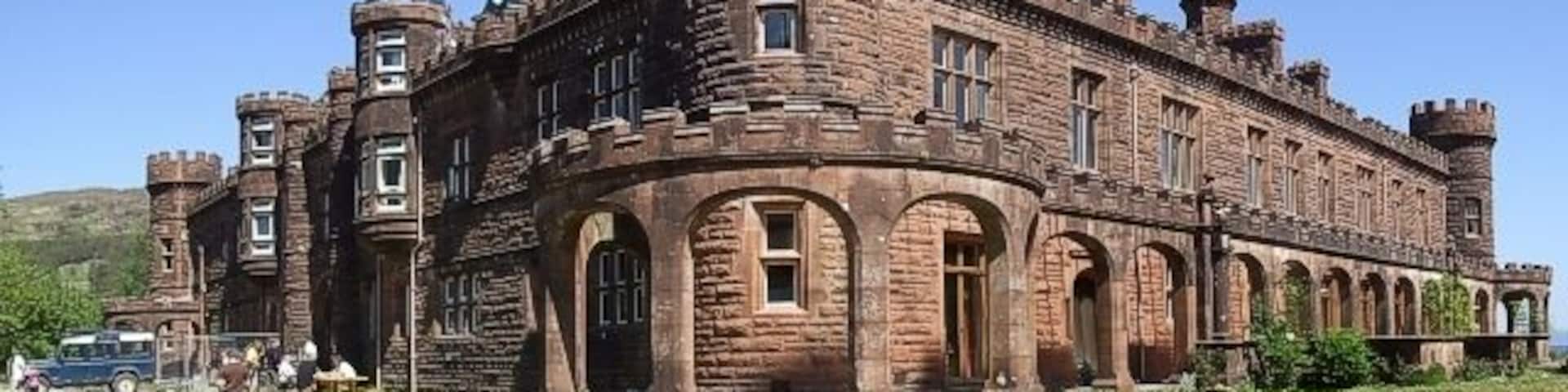 Kinloch Castle from SW This view of Kinloch Castle is from the South-West, looking directly northeastwards. It shows quite well the unusual open-topped loggia which runs along three sides of the castle. The western side - which is the rear of the castle - seen here on the left is the only side not to have this appendage. There is a hostel in this rear section of the castle - see http://www.isleofrum.com/placestostay-bb,.html
