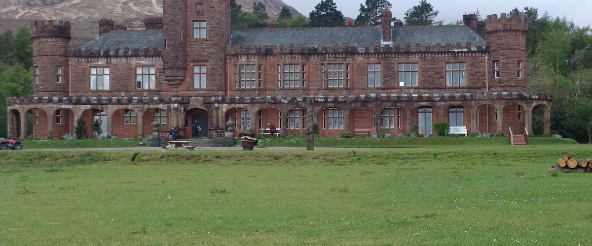 A large, historic brick building with a tower, arched windows, and a courtyard.