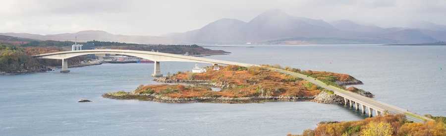 A bridge spanning a fjord with a mountainous backdrop.