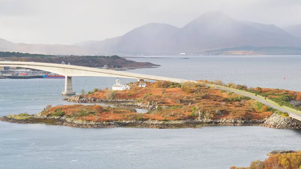 A bridge spanning a fjord with a mountainous backdrop.
