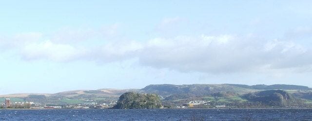 Dumbarton from Langbank. Dumbarton Rock is in the centre. The red brick tower to the left is all that remains of the once dominant Ballantines distillery building 366291 in the centre of the town (demolished 2006/07). The gasworks can be seen to the right of the rock, with Dumbuck Quarry on the far right. The Kilpareick Hills are in the background.