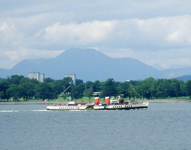 A riverboat on a river with mountains in the background.